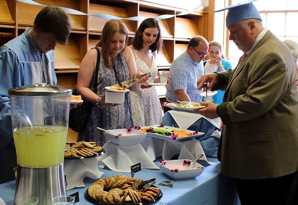 Graduate students get food at a buffet table